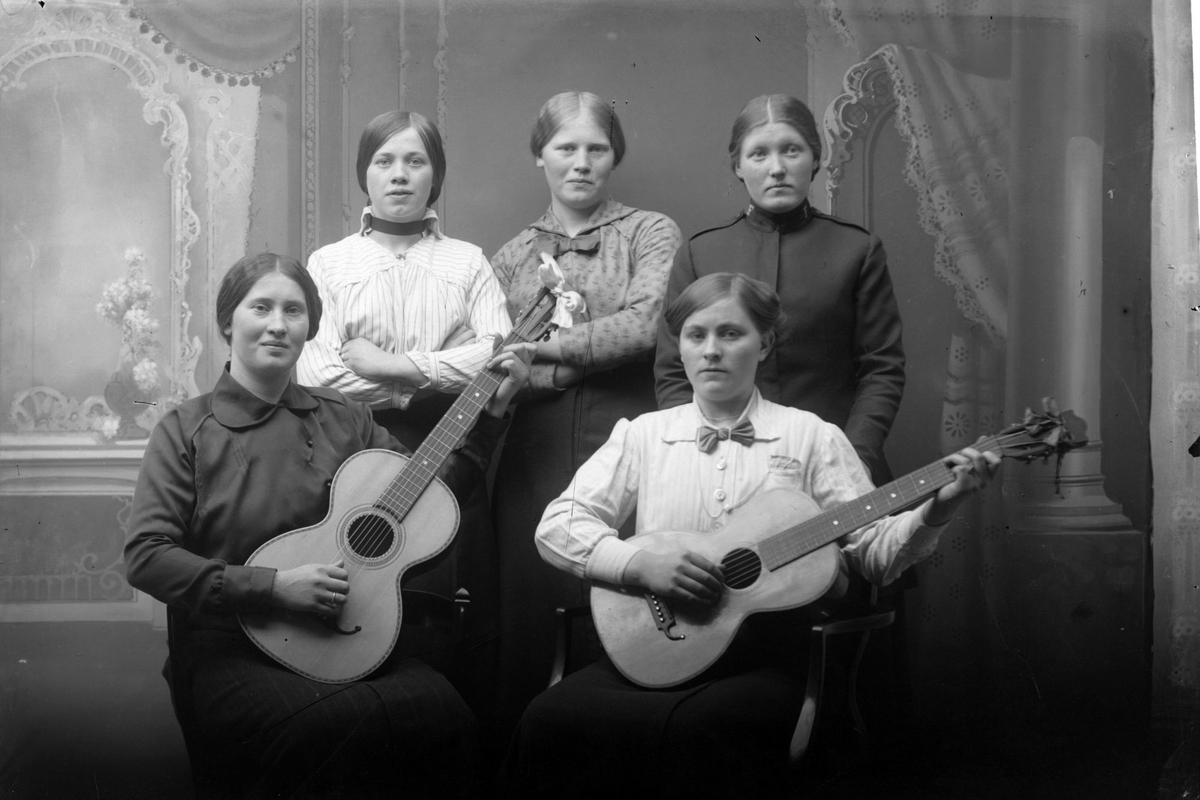 Studioportrett av fem kvinner, to av dem med gitarer. En av kvinnene har på seg Frelsesarméens uniform.