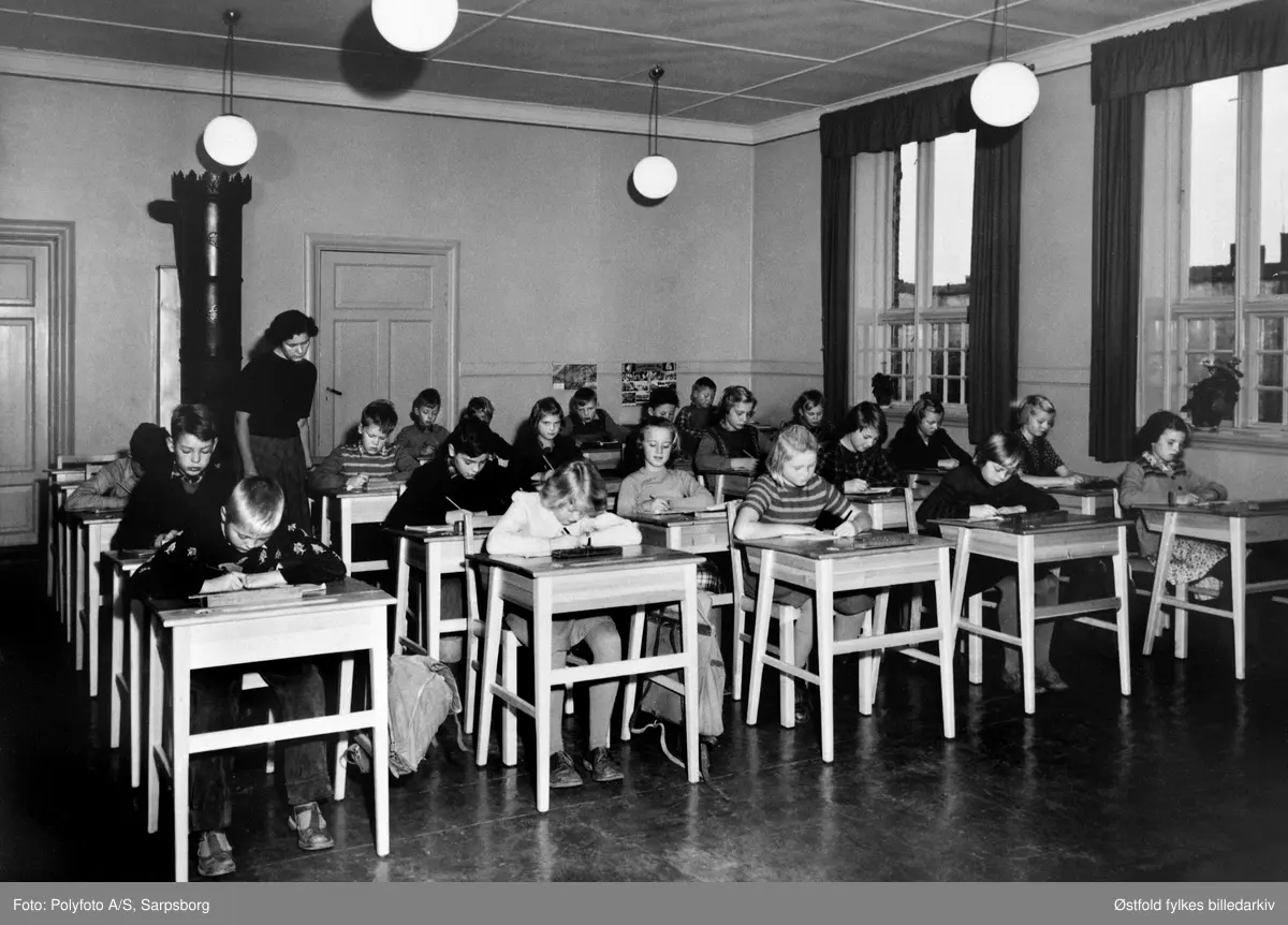 Skoleelever sittende bak pultene sine i klasserom ved Kirkegaten skole, Sarpsborg 1951. 21 elever. Lærerinne Berit Feddersen (f. Simonsen). Ingen navneliste. Se ØFB.1990-00123.