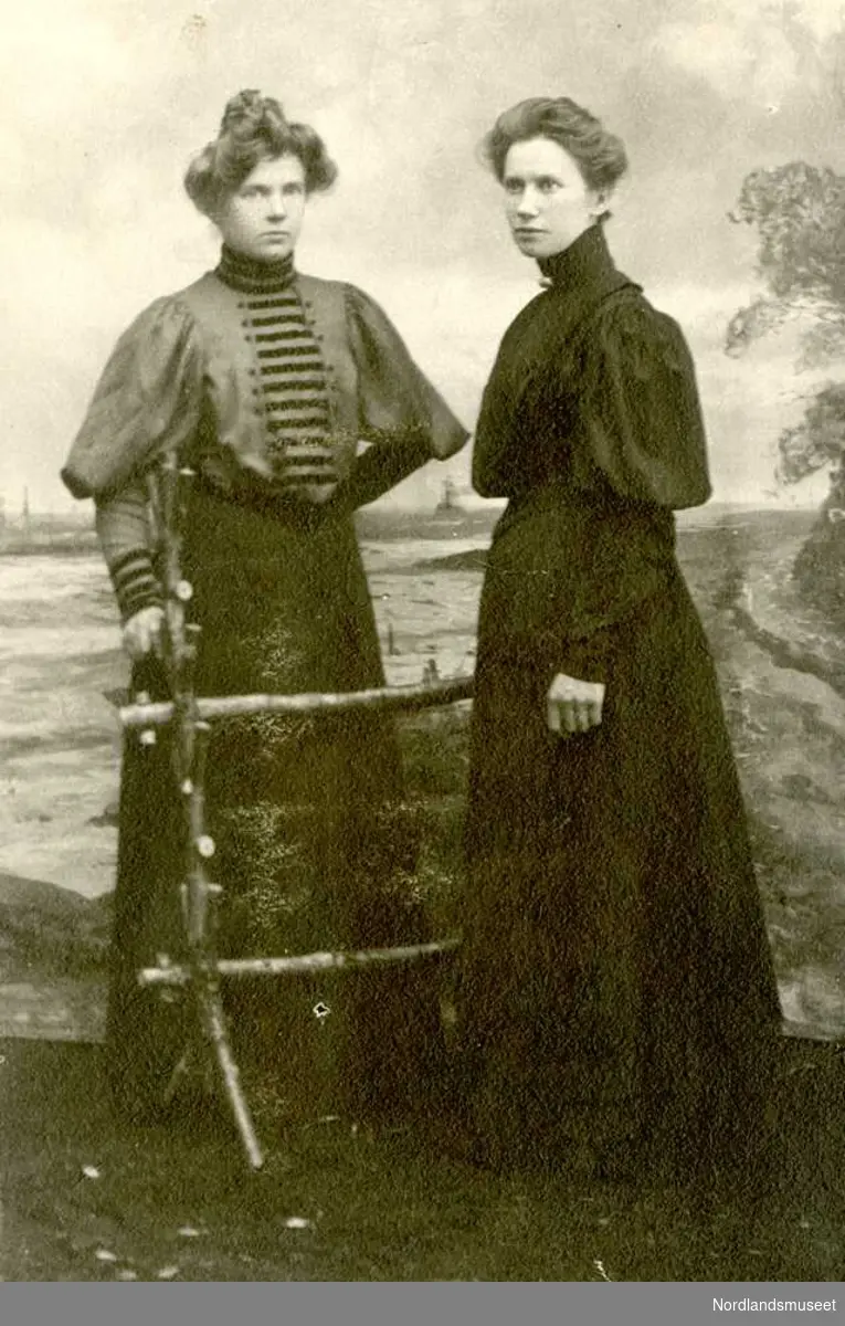 Portrett. Av to unge damer. Til høyre fru Julie Kanstad, g.m. Hans M. Kanstad. Begge er kledd i mørke skjørt og bluser med skinkearmer.