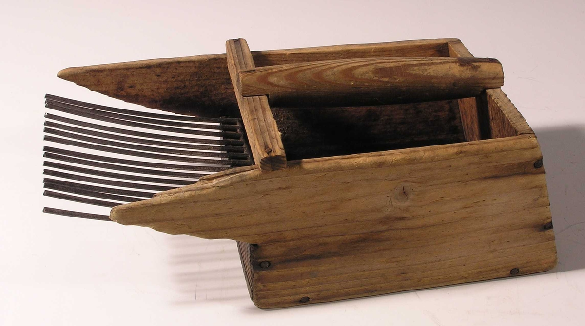 Form: åpen boks med håndtak tvers over, ståltrådtenner foran
