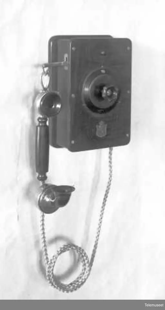 Telefonapparat, lokalt veggapparat i tre, mtlf.hengende, for 10-30 e.lj. KLokke likestrøm. Elektrisk Bureau.