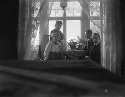 Interiør, 2 menn og 2 kvinner ved bord