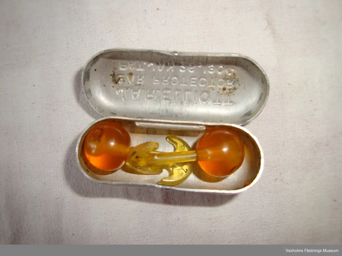 Öronproppar, användes under första världskriget, i etui av aluminium. Engelskt patent. Märkt J.A.R. Elliott. Ear Protector. Pat.Jan.26.1904.