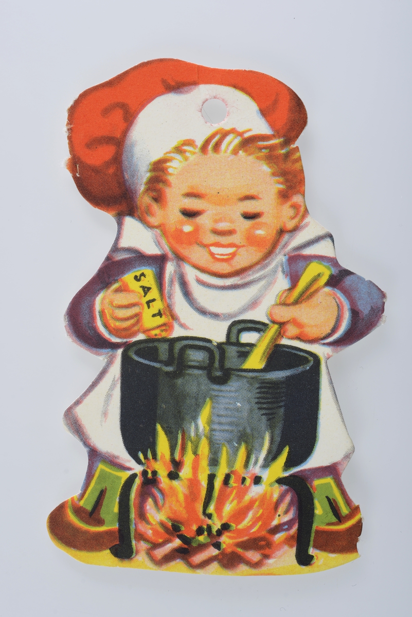 Lyshåret gutt med nisselue lager mat i jerngryte.