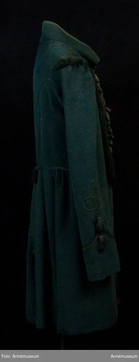 Grupp C I.
Bigeschen är tillverkad i mörkgrönt kläde och fodrad med grön boj i livet, linne i ärmarna.