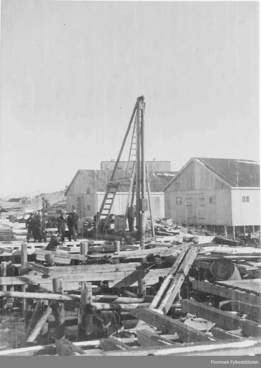 'Kirkenes mars 1946. Det blev arbeidet kontinuerlig med ut- bedring avkaiene, grunnlaget for all ilandførsel av bygnings- materialer.' Herer arbeidet i gang.