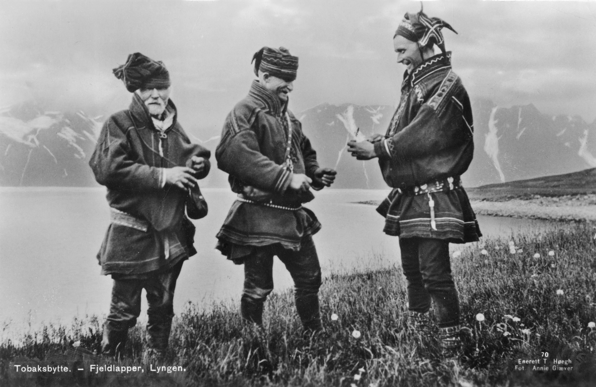 Tre menn i samedrakter, Lyngen, Troms. De bytter tobakk. Fra postkort.