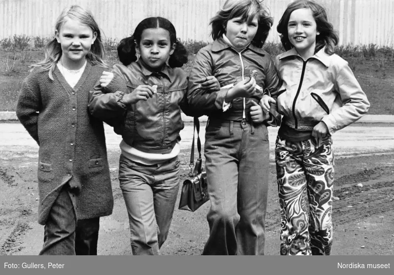 Barn i stockholmsförorten Tensta, fyra flickor går i armkrok på en grusväg.