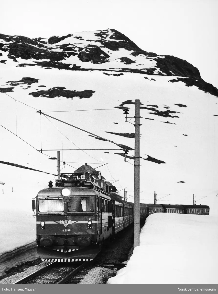 Elektrisk lokomotiv El 14 med vestgående "Bergensekspressen" ved østenden av Sandåvatn, med Sandå vokterbolig og Finsenut i bakgrunnen