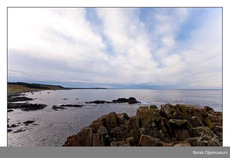 Fotografi av kysten på Lista med sprukne svaberg, hav og himmel.