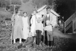 Gruppebilde av voksne og barn, tatt i slåttonna. Laftet uthu