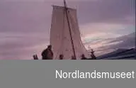 4 1/2 roms nordlandsbåt ved Bodøsjøen. Råseil. Flere personer ombord.