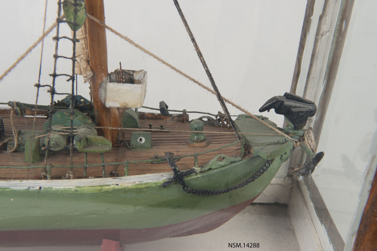 Enkel helmodell (sjømannsmodell) av hvalbåt i monter. Grønt skrog, mast, skorstein, 2 lettbåter, hvalkanon.