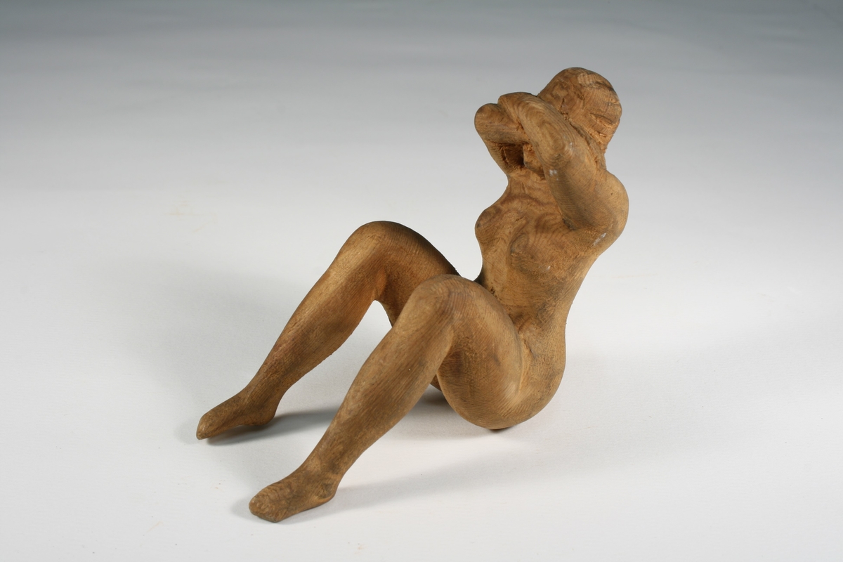 Figur av naken kvinne, sittende med armene foran ansiktet.