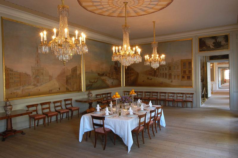 Spisesalen i Stiftsgården, med dekket bord, veggmalerier og tente lysekroner