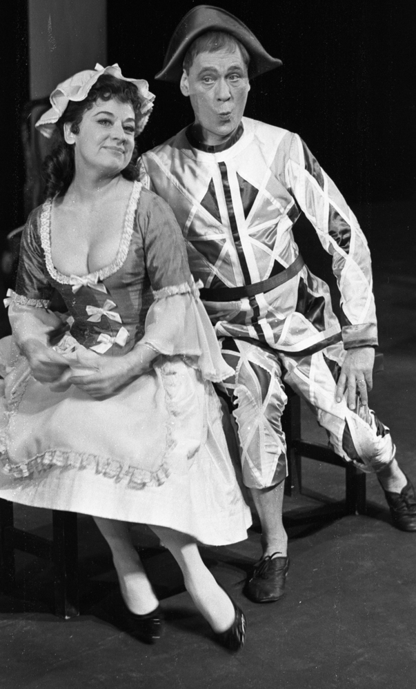 Calle Eriksson, Lustspel på Hjalmar Bergman 5 februari 1966

Två skådespelare, en kvinna och en man, agerar i ett lustspel på Hjalmar Bergmanteatern. De är klädda i 1700-talsinspirerade kläder och sitter tillsammans på en bänk på scenen. Skådespelerskan är klädd i klänning, hatt, strumpor och pumps. Hon håller i ett papper. Skådespelaren har jacka och byxor i rutigt material i Harlekinstil, svarta skor och en trekantig hatt på huvudet.