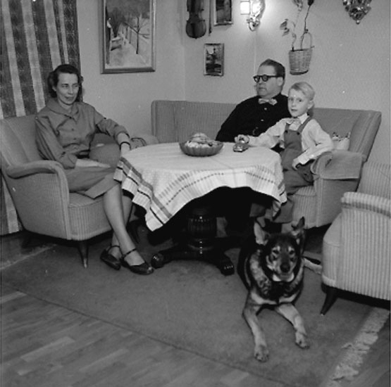 Rumsinteriör, familjegrupp tre personer och en hund.
Sixten Eriksson