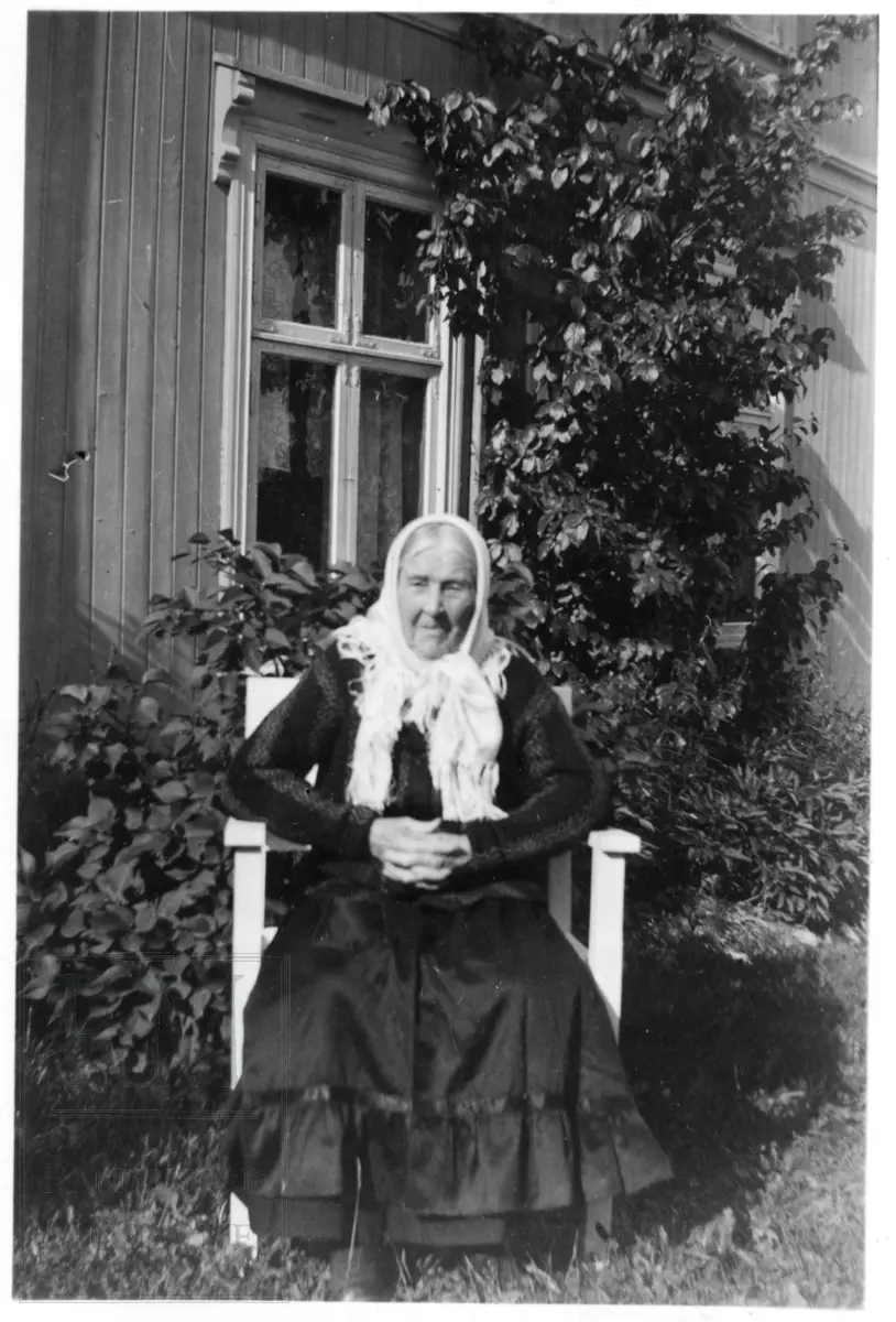 Gammel kone sittende i hagen, bilde 1 i stasklær og på bilde to med en katt på fanget. Syverine Flødsveen.