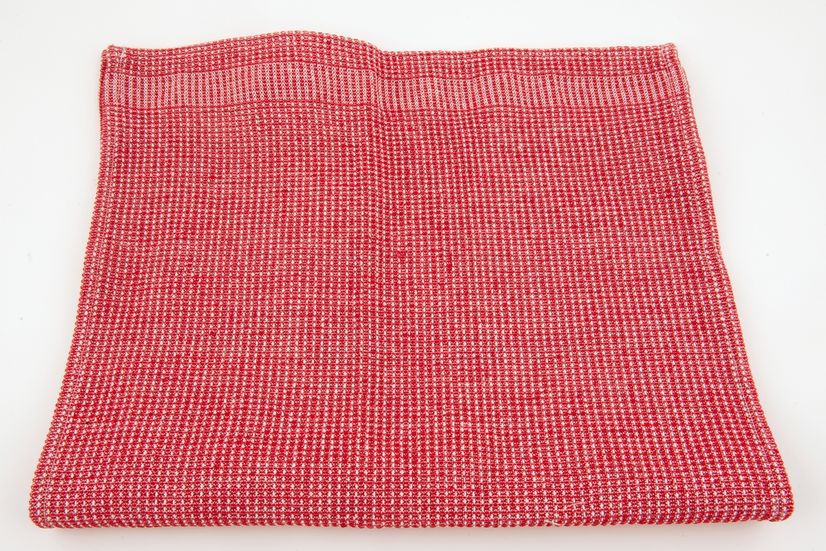 Rødt kjøkkenhåndkle med hvitt rutemønster.