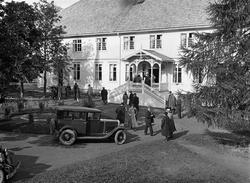 Personer og biler foran hovedbygningen på Rogneby øvre/Toten