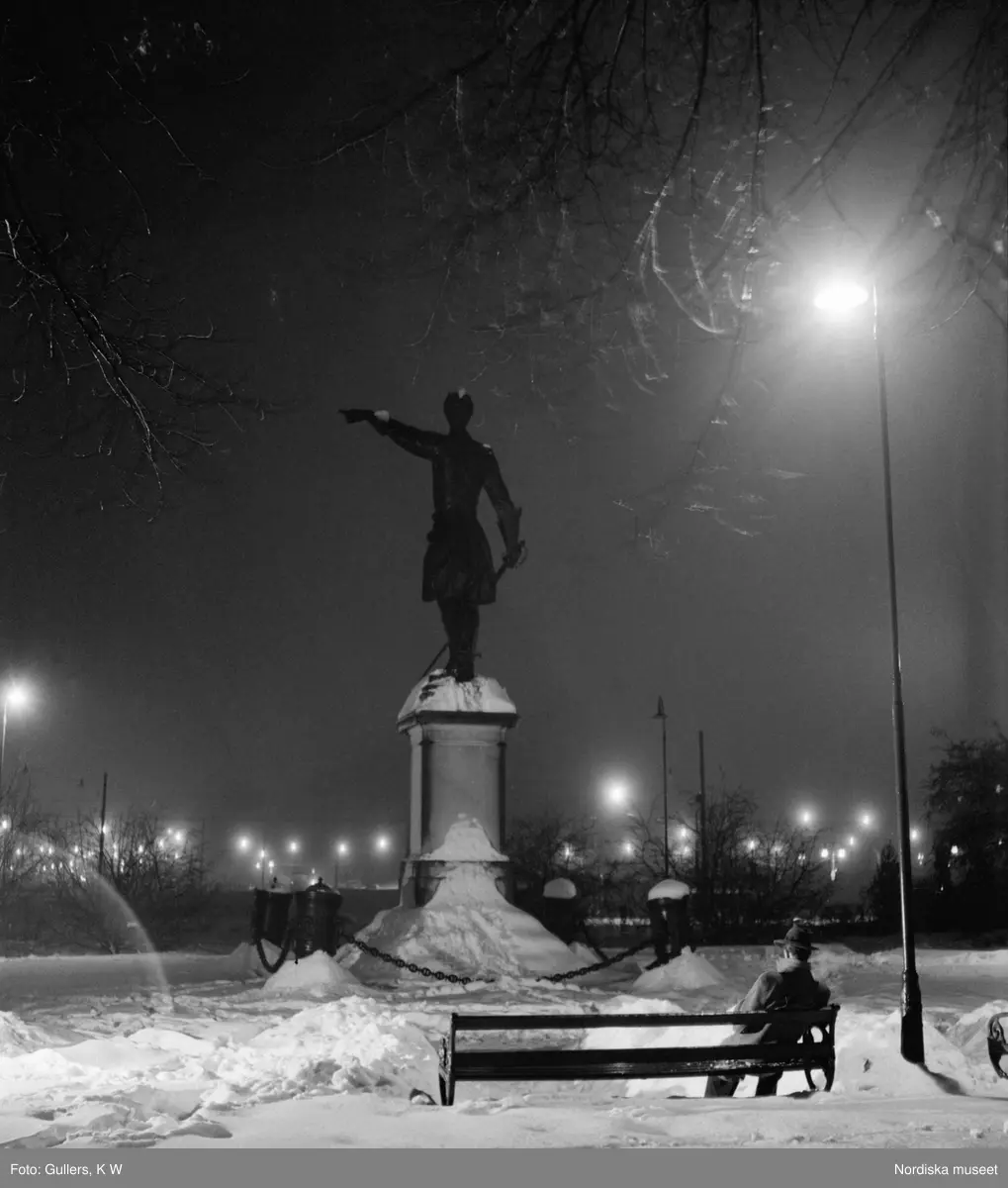 "En hemlös yngling sittande på parksoffan bakom Karl XII:s staty." Kungsträdgården, Stockholm.