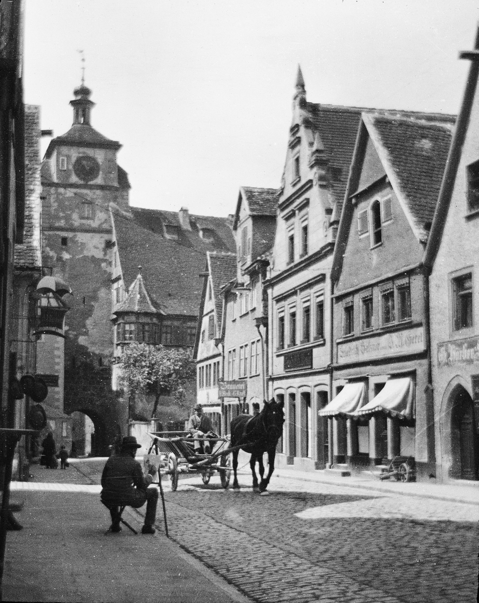 Skioptikonbild med motiv av man med häst och vagn på gata i Rothenburg.
Bilden har förvarats i kartong märkt: Rothenburg III. 1901. 9
