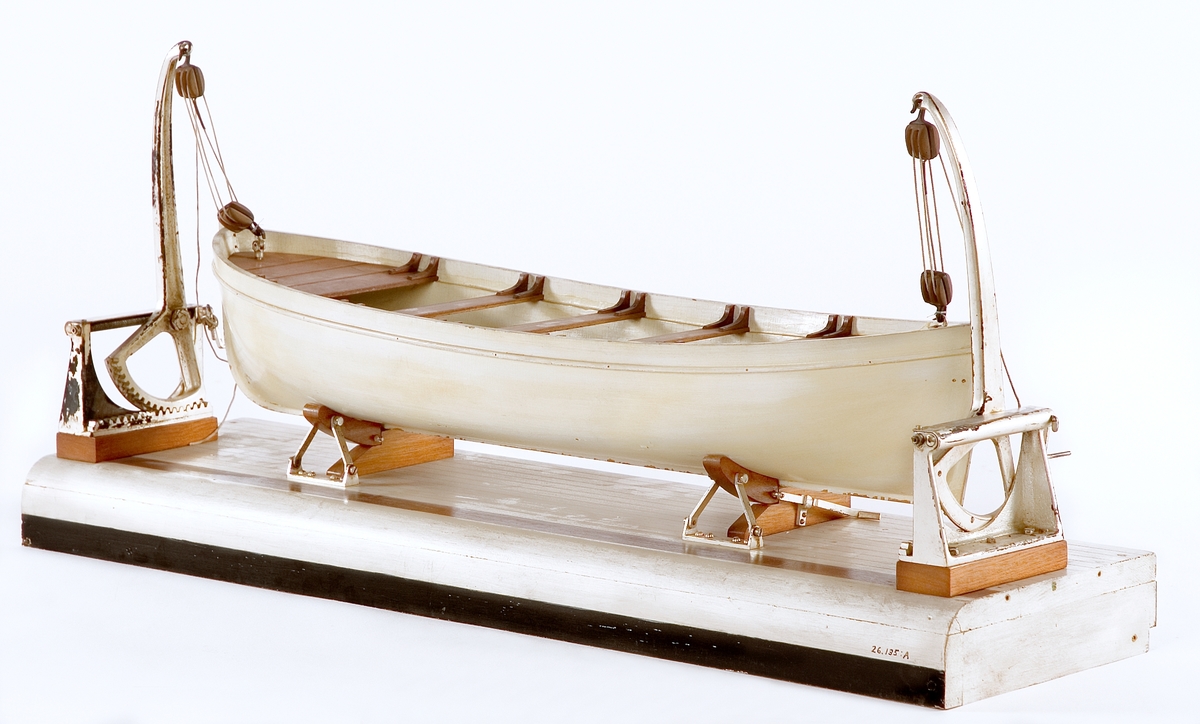 A) Modell av däcksektion med en livbåt och 2 dävertar av Welins patent.