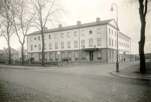 Kv. Midgård, S:t Olofsgatan 26. Stora Hotellet, Falköping. Den 29 maj 1923 motionerades om uppförandet av ett tidsenligt hotell i staden. Ritningar utarbetades av arkitekterna Båld, Borås och Ture Svanberg, Göteborg. Den 12 mars 1928 konstituerades hotellaktiebolaget Midgård och den 1 nov. 1929 stod Stora Hotellet färdigt. Det hade då dragit en kostnad av 640 000 kr. År 1967 genomfördes en omfattande om- och tillbyggnad. Ovanstående foto är från omkring 1935, i varje fall före tillbyggnaden för posten år 1939.