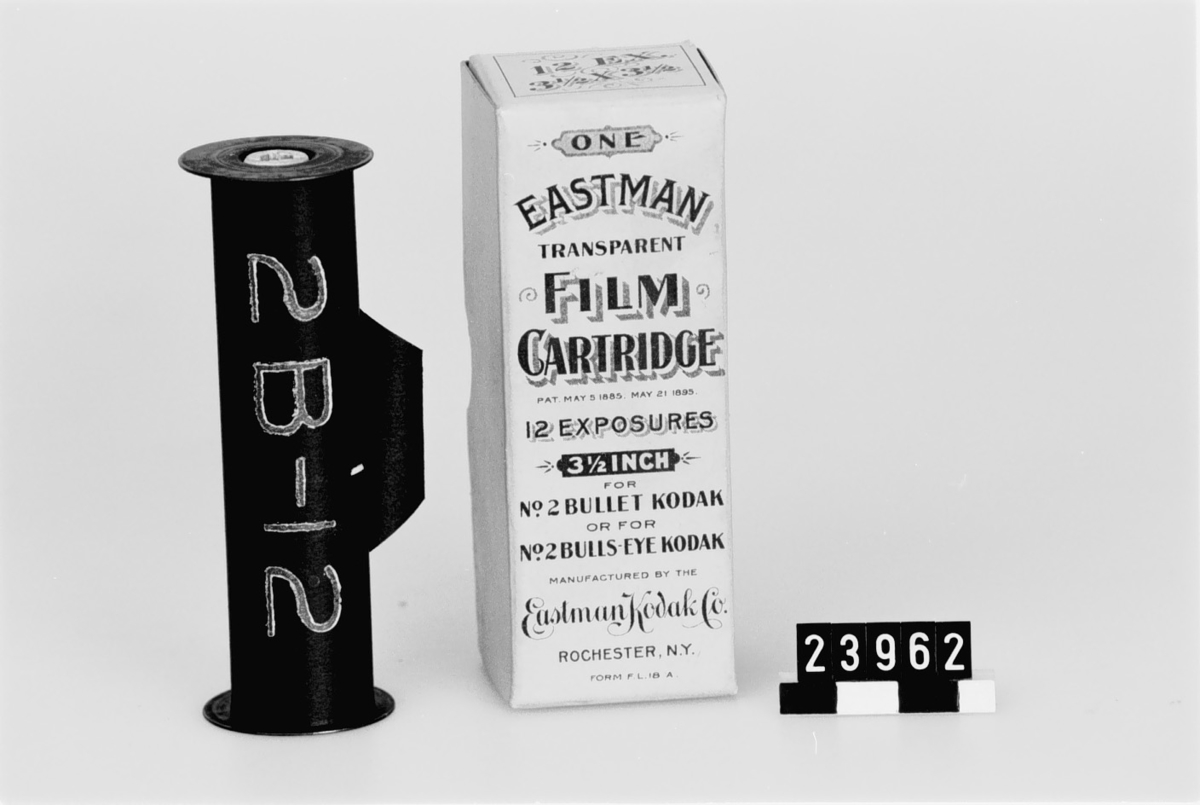 Spole av trä med gavlar av förkopprad järnplåt till Eastman transparent rullfilm 3 1/2 x 3 1/2 eng. tum i originalask. Svart skyddspapper med bildfältsiffror.