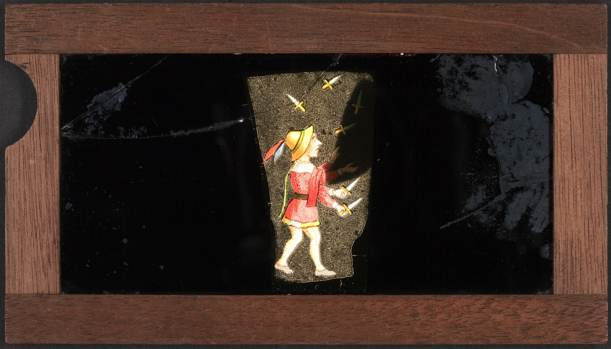Ljusbild för laterna magica med motiv av liten man i hatt som jonglerar med knivar.