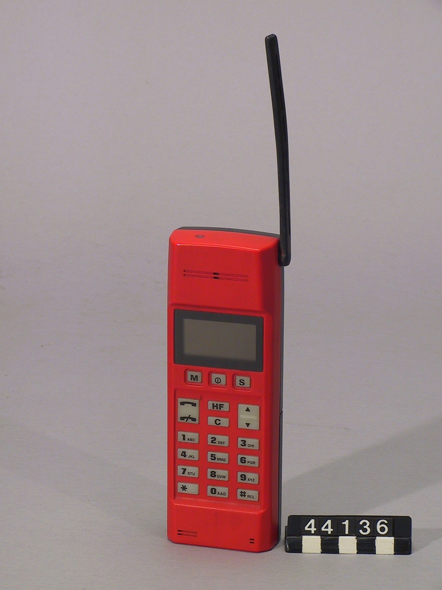 Handhållen NMT 900 mobiltelefon. Demoexemplar, färgförslag i röd kulör, med Nickel-Cadmiumbatteri märkt: 95/11. Ej i produktion.