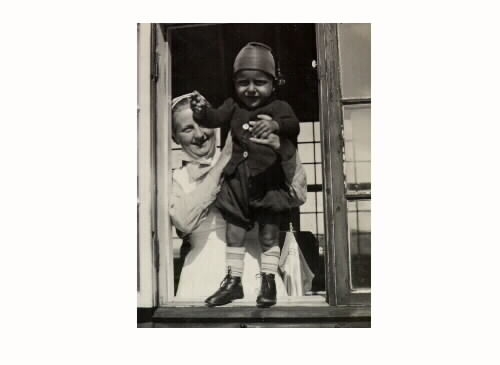 En sköterska håller upp ett litet barn i ett öppet fönster på Kustsanatoriet Apelviken. Där vårdades barn med körteltuberkulos.