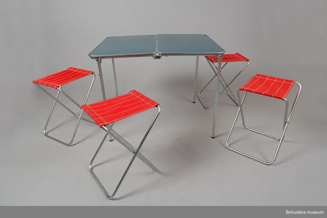 Originalförpackning med ihopfällbart campingbord av stål och fyra pallar klädda med rött syntettyg, "Campingsats".