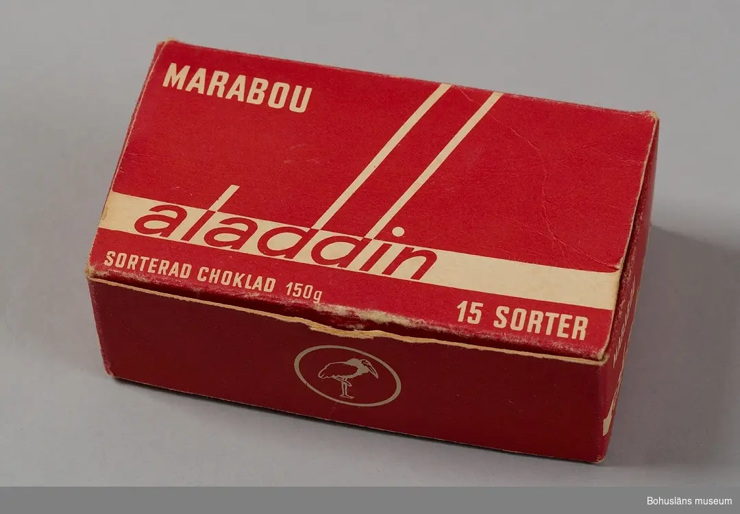 Ask av papper, röd med vit skrift. "Marabou Aladdin sorterad choklad 150 g. 15 sorter".