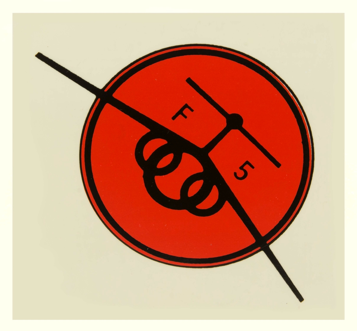 Två dekalar 1 div F5, flygförarmärke. 1) Rött E på blå bakgrund, korsade svärd som krönts av tre kronor. 
2) Röd cirkel med svart ram, F5 i svart text.