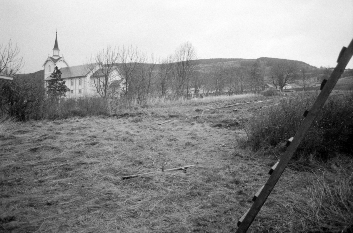 Kvæfjord kirke. I forgrunnen en stige og en ljå i nyslått gress.