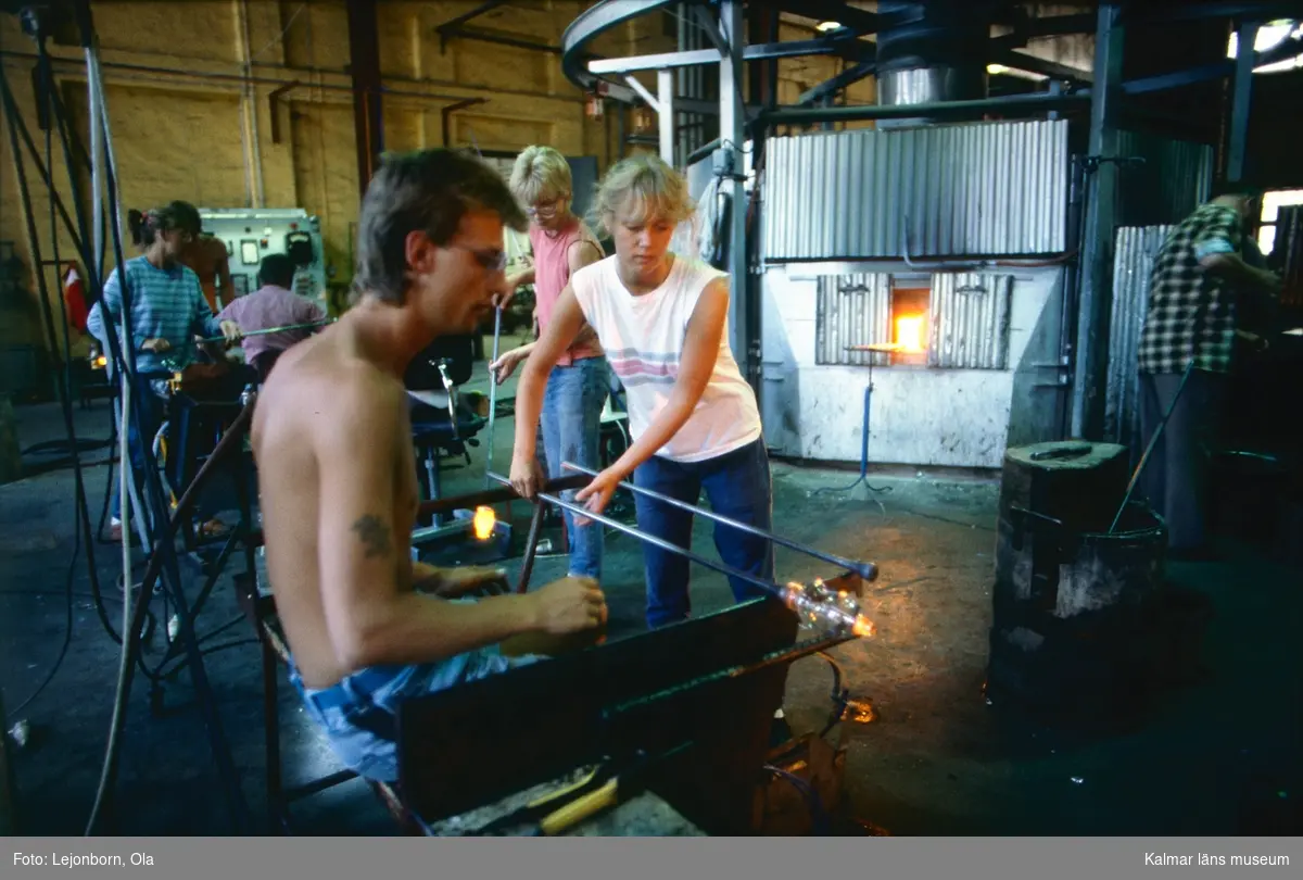 Glasblåsning vid Orrefors Glasbruk.
En benmakare ska dra ut benet på ett vinglas, som först värmts i en invärmningsugn.