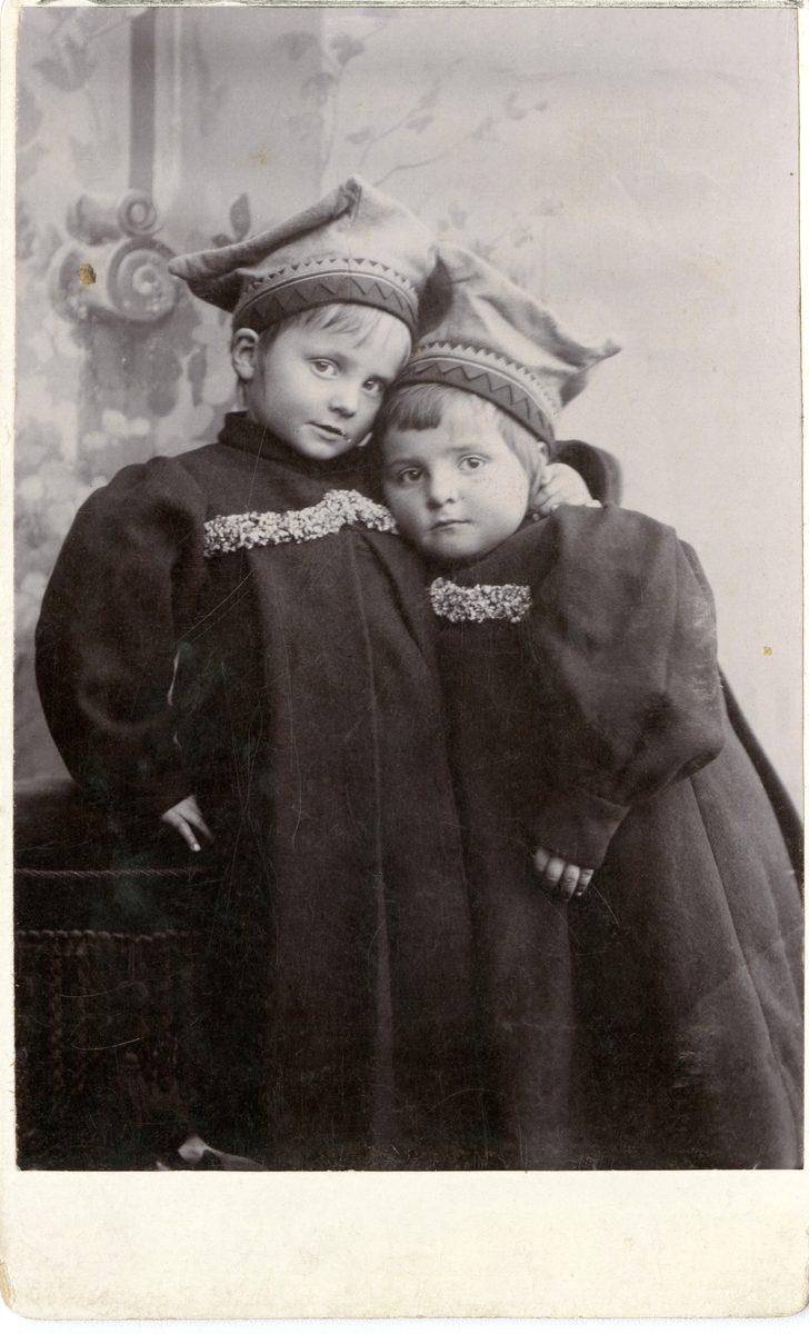 To barn iført lue og lange kjoler.
