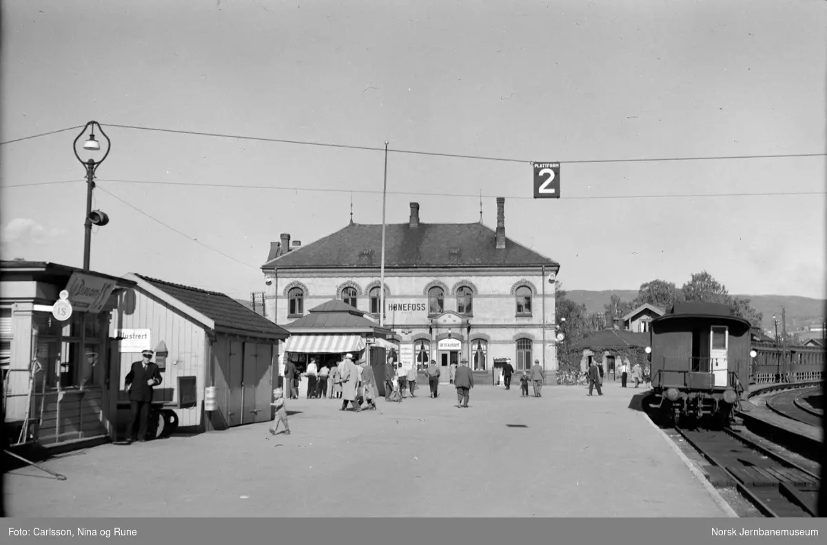 Hønefoss stasjon med reisende og persontog mot Randsfjordbanen