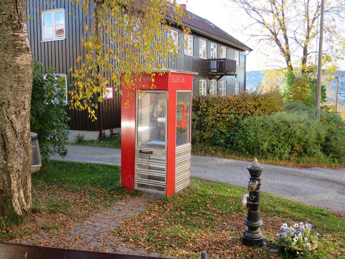 This is the story of how Norway’s most important conversation-space was designed by a young, freshly graduated man from Bergen.

“Norwegian architects are hereby invited…”
In the autumn of 1932, Oslo Telefonanlegginitiated an architectural competition. Finally, Oslo would get its own telephone booth. The city had had so called “talking-stations” from 1885, which in turn were overtaken by automatic telephones 
 only available at selected Narvesen kiosks. The state 
was of the opinion that now was the time to offer the public a better service; public telephone booths open 24/7, like the ones they already had in Sweden and England. But what would they look like, these new telephone booths? What considerations would it
 be necessary to take when designing it? The telegraph board developed a detailed list of demands and restraints: “The booth is intended to be placed outside on the streets and squares and need to be designed so that snow and ice does not hinder the opening and closing of the doors,” they wrote. “To prevent vandalism, theft, uncleanliness etc. inside the booth, it needs to be designed so that from all angles one may see what is going on in there.” Additionally, it would need to withstand storms and bad weather, and “preferably also being whipped by rain mixed with seawater” 

This was not all: The appearance would have to be «pleasing». The booth also needed to be movable, so that it could be taken in to be serviced at Telegrafverket’s main workshops. The reqired material was iron, and the surface was to be spray painted  preferably using car-body paint. There was a requirement for “a writing shelf, a pack shelf, and a suitable place for the telephone catalogue.” Also, there would need to be an illuminated TELEFON  sign, easily visible from all four angles. The total cost for each booth should not exceed 1000 kroner. The first prize for coming up with such a product was 800 kroner.

“Norwegianarchitects are hereby invited to partake in a competition for the design of a telephone booth…”  

The man with the solution
«At some point in 1932, Georg Fredrik sat at a party in Bergen. Maybe he felt a bit lost and forgotten as he often had throughout his life. He retreated to a quiet corner, took out a pencil and strted doodling on a matchbox.  According to my mother, this was how the telephone booth came into being.” In the book “Norges lille røde  historien om telefonkiosken,” Lars Fasting describes his father, the man who is far less known than the iconic architctural structure he left behind. Georg Fredrik Fasting was from Bergen, born into a family of working people and smallholders. One unusual facet of Georg Fredrik was that he was born without ears. His mother made sure he learnt to speak, read and write, 
ut Lars Fasting indicates that his father would seek refuge in drawing when the social challenges became too much to bear. And in the end drawing became his profession. In 1924 he secured a guarantor for a student loan, and started studying to become an a
rchitect at the NTH. Throughout the 1930s he entered several architectural competitions, with drafts produced, according to his son, “after work and in the late hours of the night.”

His efforts were not wasted. Out of 93 entries, with names such as “Flirt”, “Brrr”, “Ring” and “Amor”, the jury selected Fasting’s submission, “RIKS” as the new telephone booth: “The draft shows a strikingly simple solution to the task, technically as well as aesthetically well worked out.”

Taut and provident
Simple and aesthetc are the keywords here. Fasting had designed a booth pointing towards the future, and to modernism. Just how modern it was can be seen by comparing RIKS to the British telephone booth, also designed in the interwar-era. While the British version with it classicistic style is looking back to the heyday of the empire, Fasting’s booth is progressive and functionalistic. Like most Norwegian architects, Fasting broke with the classicistic style of architecture after the Stockholm-exhibition in 1930. “After it, almost all buildings erected in Norway until the German invasion in 1940, were in the functionalistic architectural style,” writes senior curator of architecture at the Norwegian National Museum, Ulf Grønvold, in the book, “Den lille røde”.“TheNorwegian booth is a piece of functionalistic architecture, an asymmetric composition with its roof slab overhanging the word TELEFON, in bold sans seraph lettering,”concludes Ulf Grønvold.

Fashionably red
And it was red. Fasting chose a colour which was part of the modern palette. “A bright red colour, but not as shiny as a signal red, the character of the colour places it among the fashionable colours within functionalism,” states paintings conservator and researcher in NIKU (Norwegian Institute for Cultural Heitage Research), Jon Brænne. In his opinion, Fasting went for visibility without making the booth stand out too much from its surroundings. The original colour was in use up to around 1950, when it changed to signal red. Towards the end of the 1970s the clour was again adjusted towards today’s orangey red.

The design, however, has not changed. RIKS is eighty years and still looks remarkably good. That’s what makes Fasting’s telephone booth a classic  even before it was added to DOCOMOMO’s list over moden icons of design. For Telenor, the telephone booth has served as a pathway into the hearts of the public. For many, Telenor (Televerket) was synonymous with exactly this telephone booth, because this was where one would go to place a call. Having a home
phone was not common until the 1980s. As such the red box became part of the Norwegian everyday and consciousness. The symbol- and publicity value of this is hard to evaluate, but in 2007 it was time to give honour where honour was due, Telenor, in consul
tation with the Directorate for Cultural Heritage, decided to preserve 100 telephone booths for all eternity.

And what about Georg Fredrik Fasting? What happened to him? At the age of 56 an entry in his diary states: «I CAN HEAR». As the first person in th world he had undergone an operation where he had ear canals constructed and eardrums fitted. For the rest of his life, the man behind Norway’s own telephone booth could answer the telephone himself.

Source: Norges lille røde historien om telefonkiosken (2007), issued by The Norwegian Telecom Museum and Telenor Cultural Heritage.
