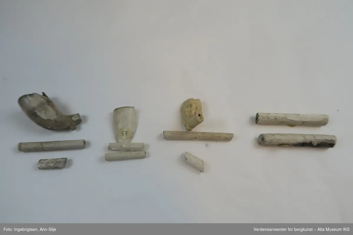 En samling fragmenter av krittpiper. Et av pipehodene er mer eller mindre hel, men med avbrukket pipehals. 

Fragmentene varierer i størrelse fra 1,5 cm til 5,7 cm i lengde og 0,5 cm til 2 cm i bredde.