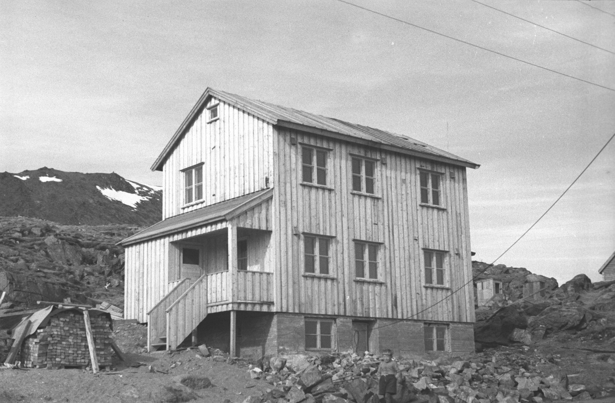 Gjenreisning. En ferdigbygd hus i Honningsvåg med en liten gutt i forgrunnen. 1946/47.