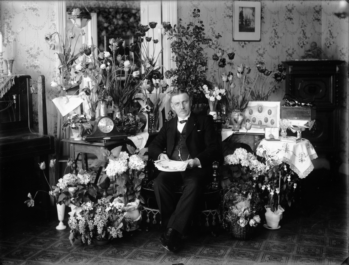 Handlare Petter Nordqvist omgiven av blommor i sitt hem, Drottninggatan, Östhammar, Uppland