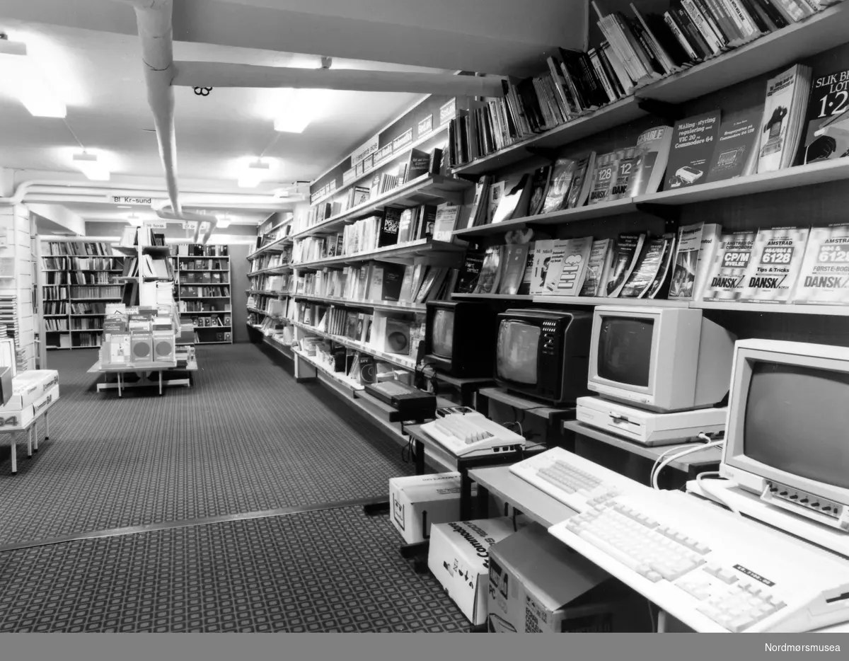 Foto fra Sverdrups bokhandel i Nedre Enggate 5/7 i Kaibakken på Kirkelandet i Kristiansund.  -- Bildet kan tidligst være fra 1987 da Amiga 500 ikke ble sluppet før det årstallet. Det er datamaskinen nederst i bildet + Commodore Amiga + Commodore 64. + 128D.  Data, IT. (Info: Hans Arvid Johansen 2018.) -- Maskinen lengst borte er en Amstrad CPC 6128. I hyllene kan man se databøker til Commodore VIC 20, Amstrad CPC og Commodore 64. Flere av disse bøkene er på dansk. 
(info: Ivar Fiske 2021).  -  Maskinen mellom Amiga 500 og Commodore 64C maskinen er en Commodore PC-1 og ikke en Commodore 128D. Det kan man bl.a. se på tastaturet. Commodore PC-1 er en IBM PC XT clone. (Info: Remi Jakobsen)



Fra Nordmøre Museums fotosamlinger.
