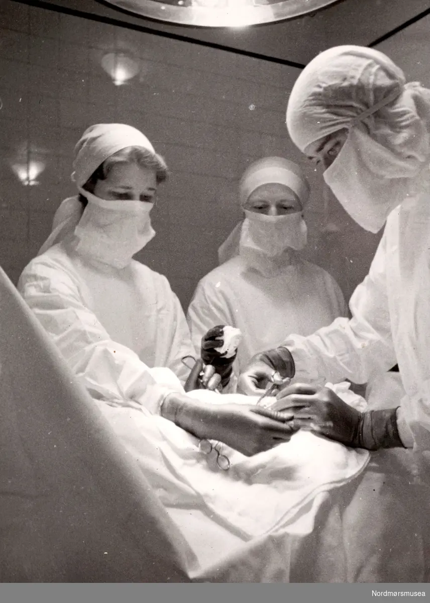 Fra operasjonsstuen, trolig i 1943, med en kirurg og to sykesøstre. Bildet er trolig fra Oslo, og elevene holder til ved Røde Kors' søsterhjem. Fra Ida M. Knudtzons fotosamlinger, nå en del av Nordmøre museums fotosamlinger.