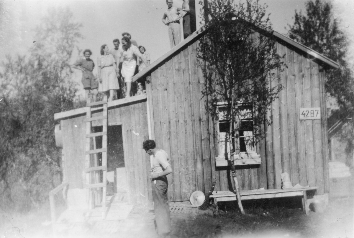 Kvinner og menn fotografert på taket til brakke i "Finnmarksleiren".