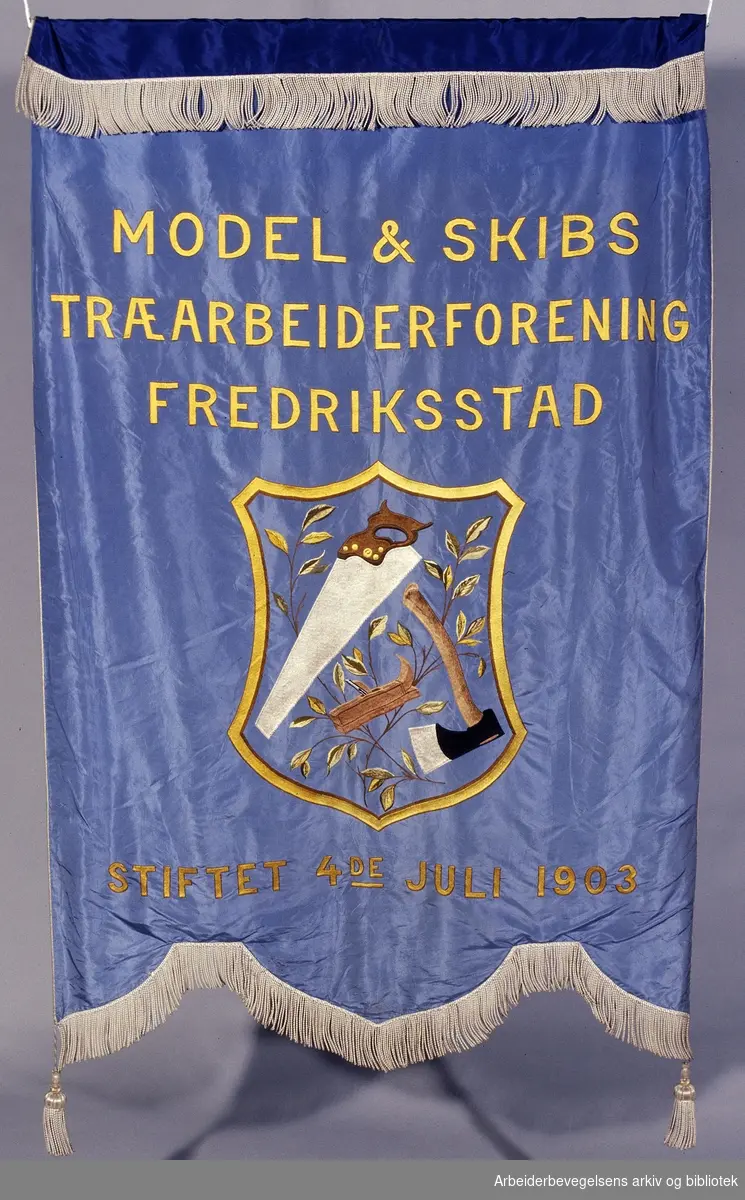 Model- og skibstræarbeiderforening, Fredrikstad.Stiftet 4. juli 1903..Forside..Fanetekst: Model & Skibstræarbeiderforening, Fredriksstad.Stiftet 4de juli 1903..