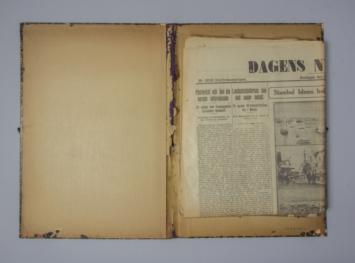 Portfölj av marmorerad papp. Sammanhållen med knytband. Rygg av lila linne. Innehåller enbart flera exemplar av Dagens Nyheter från 1912.