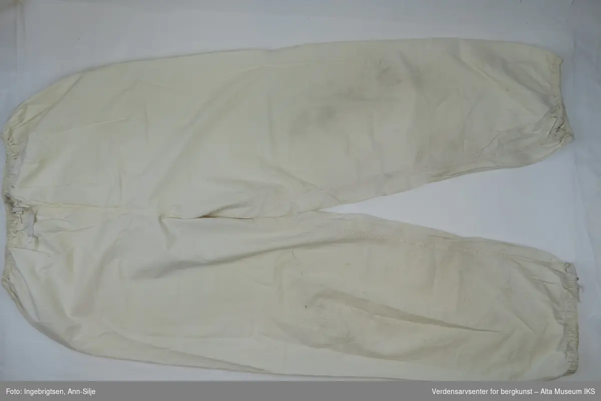 Hvit tøybukse med strikk i linningen og nederst på buksebena. Baklomme på høyre side.