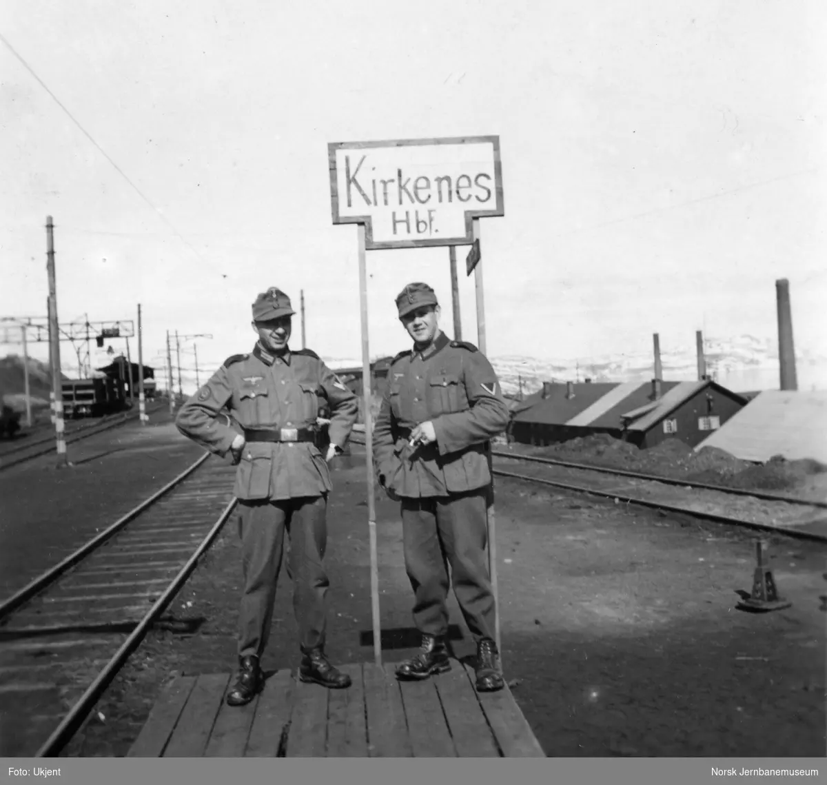 Tysk skilt oppsatt på Kirkenes stasjon - "Kirkenes Hbf." - to militære poserer